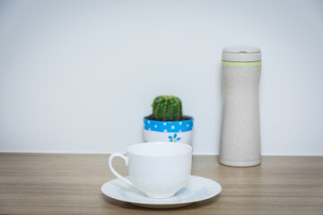 Coffee cup and thermos bottle on table.