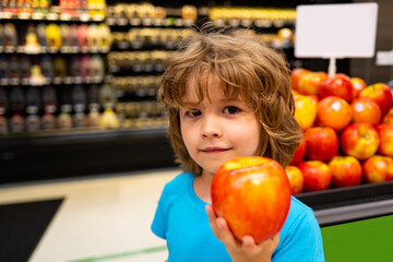 Fototapeta premium Child with an apple at the grocery store. Healthly food. Fruits. Food for children.