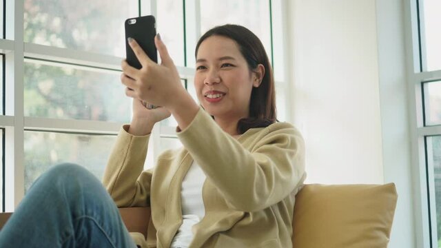 close up young asian woman holding smartphone to communicate by video call with friends and family after stay home for quarantine and new normal lifestyle concept