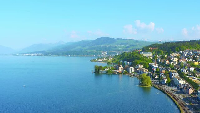 Aerial shot of Lake Zurich with town on shore, hazy mountains in distance