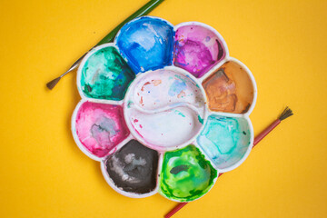 View of paint palette with different colors and paint brushes. Selective focus.