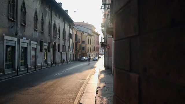 A young person riding a memorized scooter down a mostly empty city street, Vernonia Italy, slow motion