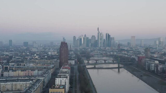 Frankfurt Skyline with Hotel tower and river main in the foreground at dusk on a misty winter morning. Drone Aerial Push In