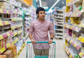 asian man with shopping cart in supermarket department store