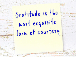 Yellow sticky note on wooden wall with wise quote