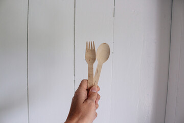 Flat-lay concept, young woman holding a bamboo fork and spoon on a white background, plastic-free...