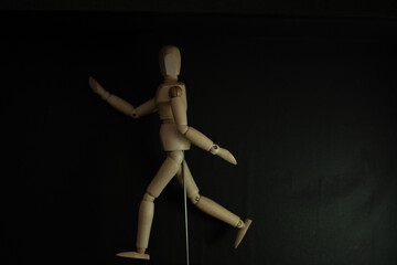 wooden mannequin running pose on black background