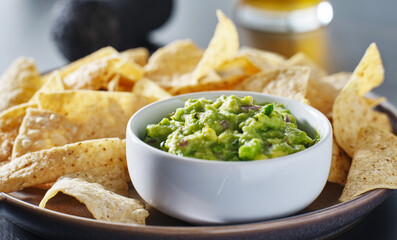 plate of corn tortilla chips with gaucamole dip - obrazy, fototapety, plakaty