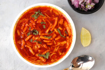 Traditional Sev bhaji or sev tamatar nu Shaak. its a  sweet & spicy tomato curry topped with sev.  Sev is a crisp fried gram flour vermicelli. Served with chopped onion and lemon. with Copy space.