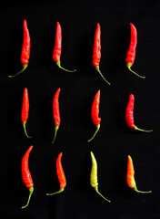 Various red chili and cayenne peppers in black background and love heart shape