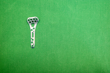 titanium plate for a radius fracture lies on a green surgical drape