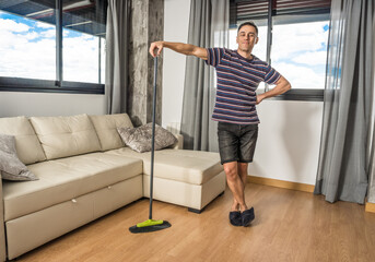 Smiling man sweeping his living room.