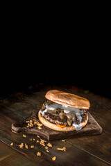  Hambúrguer de carne com cream cheese cebola crispy e caramelizada sobre mesa de madeira