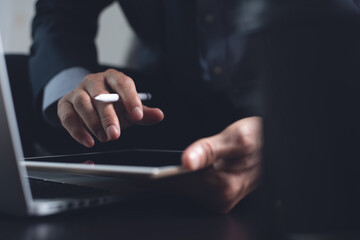 Businessman working on laptop computer surfing internet and using digital tablet in office
