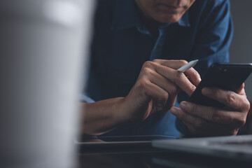 Multitasking asian business man using mobile phone working on laptop computer