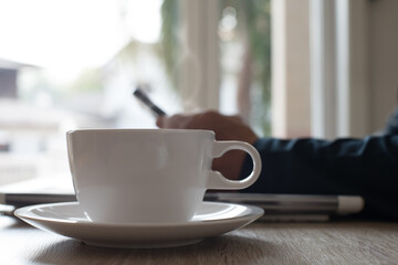 Man using mobile phone reading online news with morning coffee