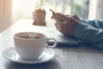 Man working from home using mobile phone with morning coffee