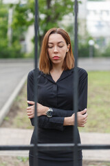 Depressed woman stands behind the bars. Consept of isolation