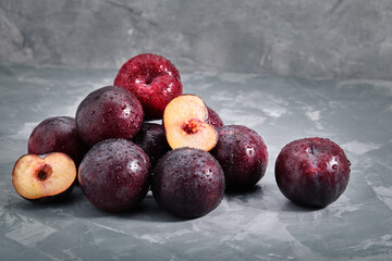 A bunch of fresh plums on a gray background, photo for grocery stores, copy space.