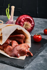 Raw chicken liver. Raw chicken fillet on a gray cement background. Copy space, eco packaging, grocery delivery.