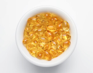Bowl with fish oil capsules on white background