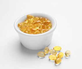 Bowl with fish oil capsules on white background