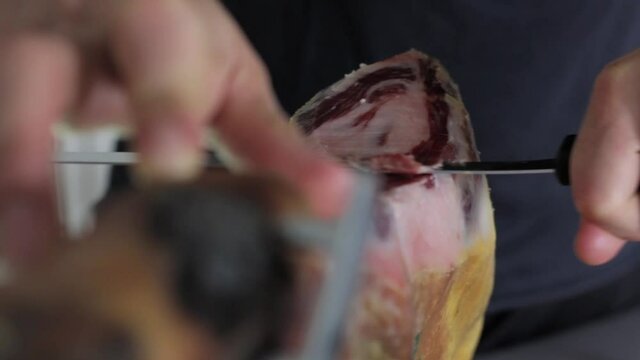 Chef cutting serrano ham with knife