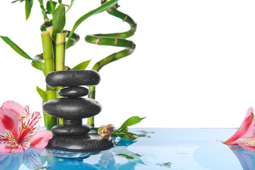Spa stones, bamboo and flowers in water against white background