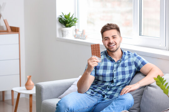 Handsome young man with tasty chocolate at home