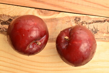 Fototapeta na wymiar Ripe juicy, organic red plum, close-up, on a wooden table.