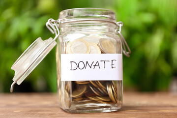 Glass jar with coins on table outdoors. Concept of donations