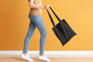 Young woman with eco bag against color wall