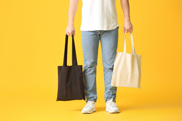 Young man with eco bags on color background