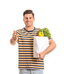 Young man with food in bag showing thumb-up gesture on white background