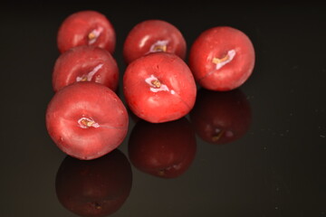 Ripe juicy, organic red plum, close-up, on a black background.