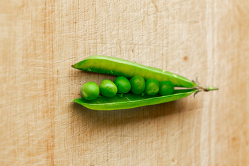 Green fresh pea pods and peas on wooden background, top view