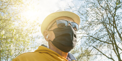 old man in sunglasses mask looks upward in garden closeup