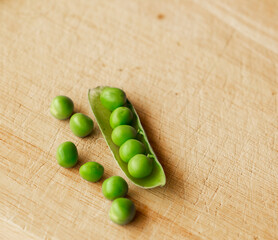 Green fresh pea pods and peas on wooden background, top view