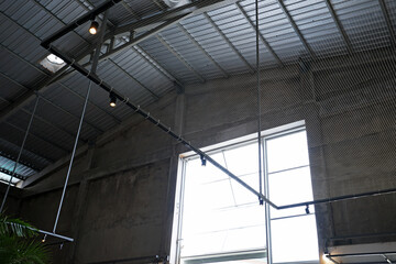 Fototapeta premium Interior ceiling design and loft architecture of old building structure decorated with cement concrete wall, industrial furniture and hanging lamp