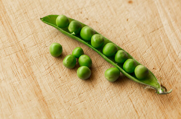 Green fresh pea pods and peas on wooden background, top view
