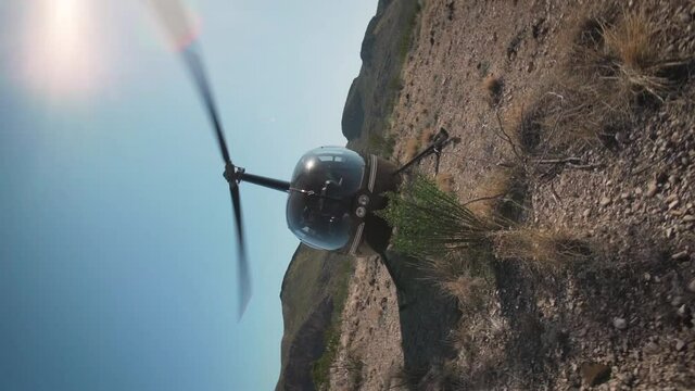 Helicopter starting up propellors turning in the desert with pilot in cockpit spinning shot in slow motion