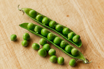 Green fresh pea pods and peas on wooden background, top view