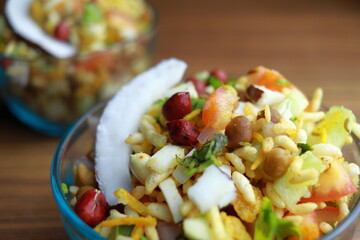 spicy puffed rice street food garnished with coconut slice, peanut, tomato and spices