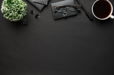 Top view of modern black office desk with blank paper sheet, notebook, pen and a lot of things. Flat lay table layout. Copy space for text.