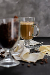 a cup of latte on a black background with pieces of white chocolate