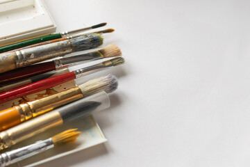 Obraz premium Different brushes for drawing multi-colored paints white background. Flat layout with place advertisement design text.