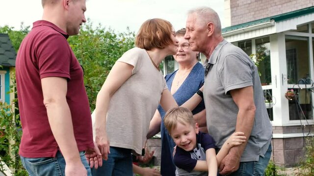 Big family meeting - grown kids visit senior grandparents, three generations meet outdoors