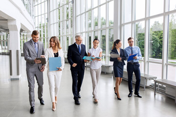 people, work and corporate concept - business team with folders walking along office building and...