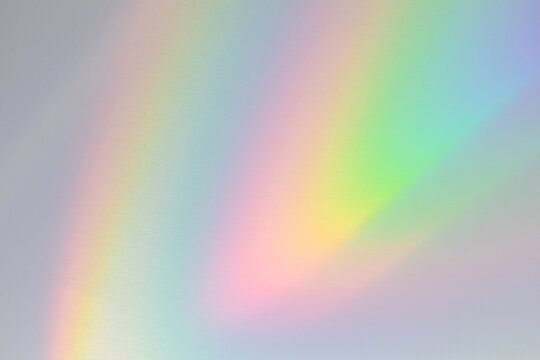  Blurred rainbow light refraction texture overlay effect for photo and mockups. Organic drop diagonal holographic flare on a white wall. Shadows for natural light effects