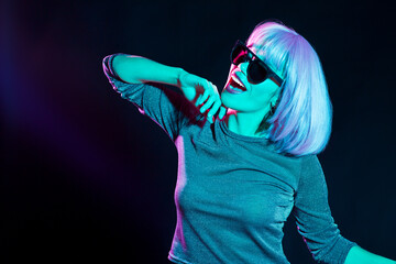 nightlife, fashion and people concept - happy young woman wearing pink wig and black sunglasses in...